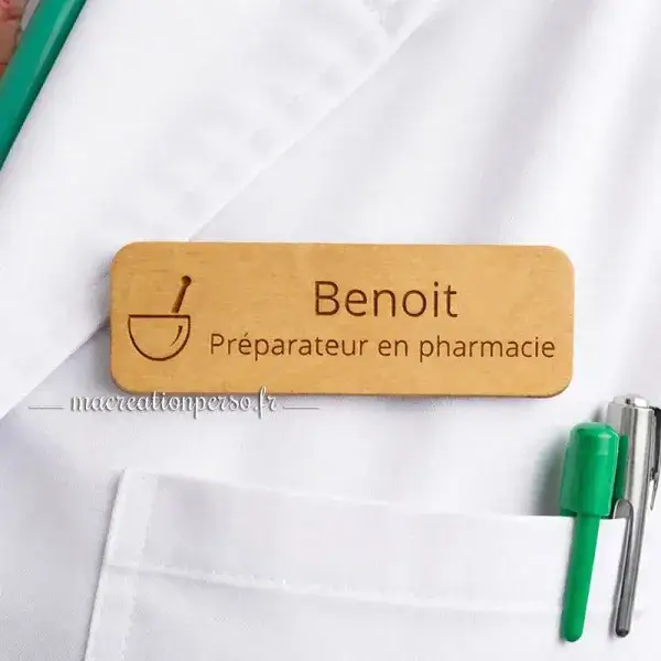 Insigne préparateur en pharmacie en bois avec prénom gravé porté sur blouse en officine pour identification du personnel