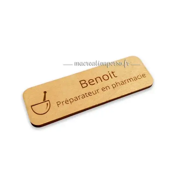 Préparateur en pharmacie portant un insigne personnalisé en bois lors de l’accueil des patients en officine