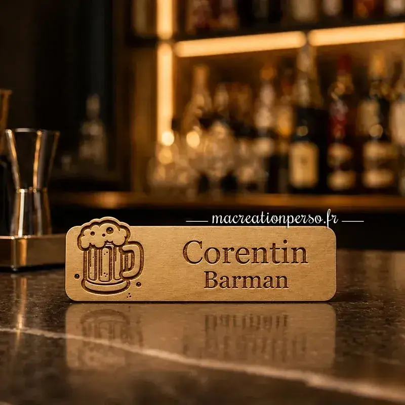 Badge barman personnalisé avec prénom posé sur un comptoir de bar