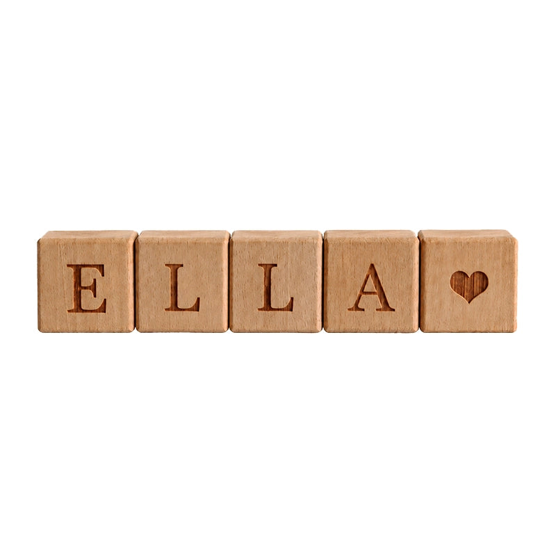 Cubes en bois personnalisés alignés formant le prénom Ella avec un cœur gravé